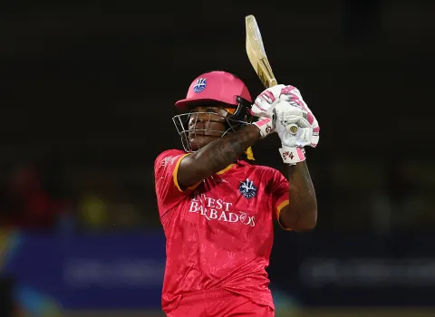 A Barbados Royals batter in pink kit raises the bat under floodlights